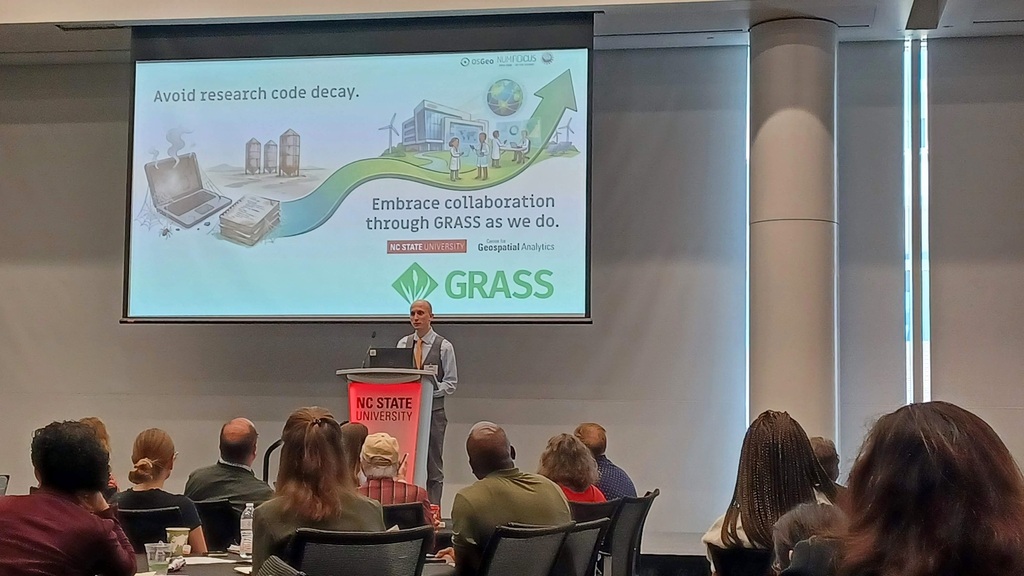 Vaclav Petras on stage with poster's graphical abstract in the background showing path from code decay to sustainable science. The text says: Avoid research code decay. Embrace collaboration through GRASS as we do. NC State University, Center for Geospatial Analytics, GRASS.